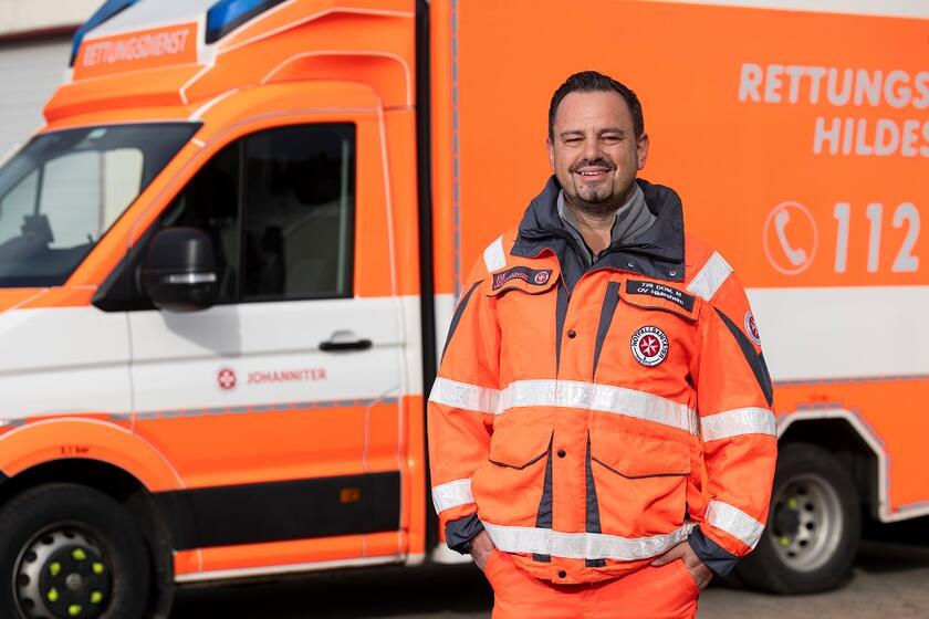 Eine Rettungskraft steht vor einem Einsatzwagen