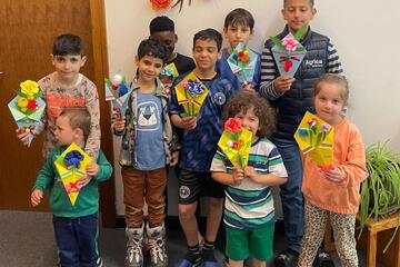 Eine Gruppe von Kindern zeigt die selbst gebastelten Muttertagsgeschenke
