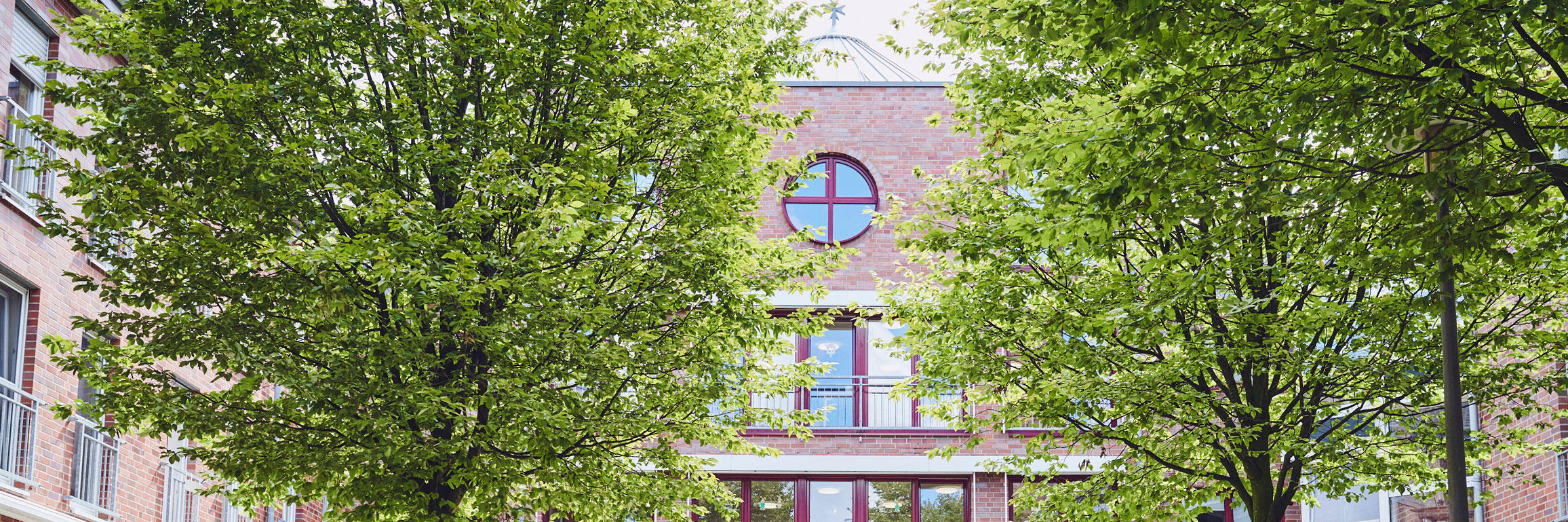 Schön gestalteter Vorplatz mit zwei Bäumen und gegenüberstehenden Bänken zum Johanniter-Stift Wuppertal