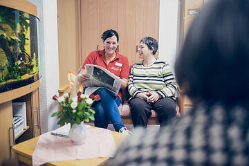 Eine Dame liest einer Seniorin vor