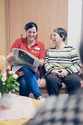 Eine Dame liest einer Seniorin vor