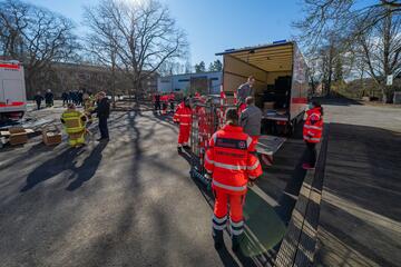 Einsatzkräfte laden gemeinsam Material aus einem LKW und bereiten den Aufbau einer Einsatzstelle im Freien vor.