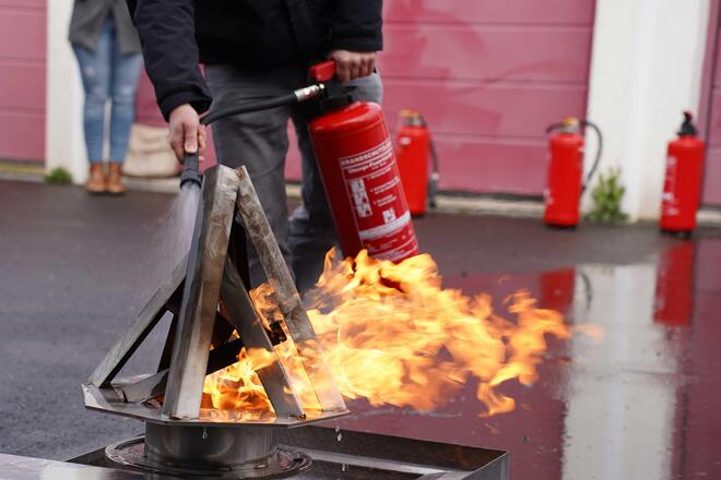 Schulung, richtiges Löschen mit dem Feuerlöscher von einem künstlich erzeugten Feuer
