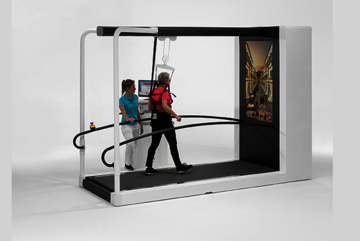 Dame mit pinkem Sportshirt wird von Therapeutin im Gang- und Gleichgewichtstraining beobachtet.