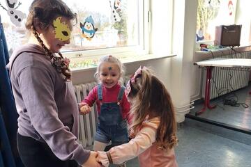 Zwei kleine Mädchen tanzen mit einem größeren Mädchen.