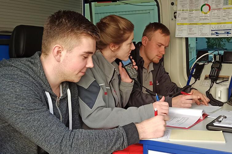 Johanniterinnen und Johanniter schauen gemeinsan in die Landkarten und testen das Funkgerät. 