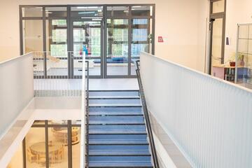 Ein Ausblick auf den Aufgang in den ersten Stock der Kita Lumi Natura mit dem Turnraum im Hintergrund.