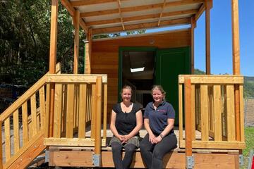 Zwei Mitarbeiterinnen sitzen vor dem Bauwagen der Waldkita in Rech