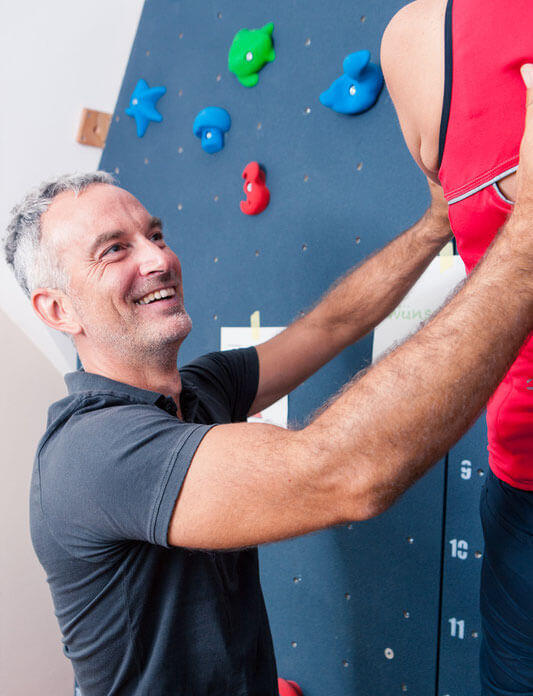 Mann an Kletterwand mit Lächeln im Gesicht 