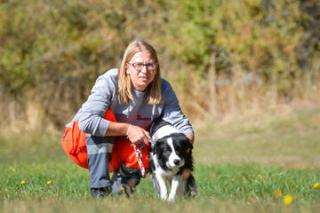 Hundeführer mit Rettungshund bei Übung auf einer Wiese