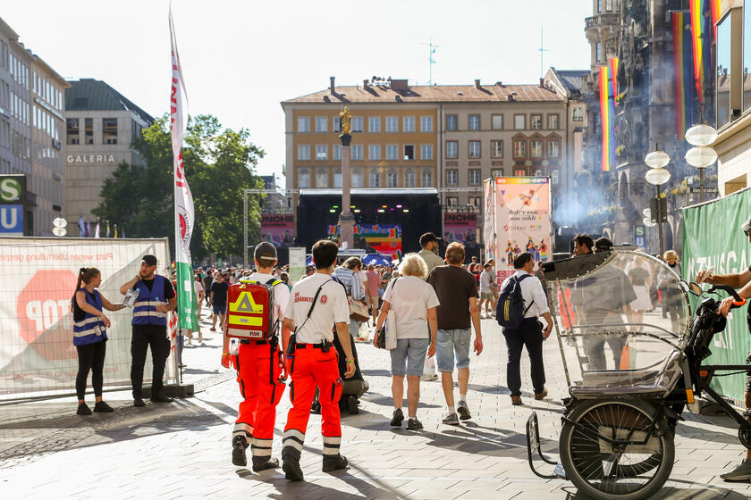 Einsatzkräfte der Johanniter mit Rettungsrucksack betreten den mit Regenbogenfahnen geschmückten Marienplatz in München.