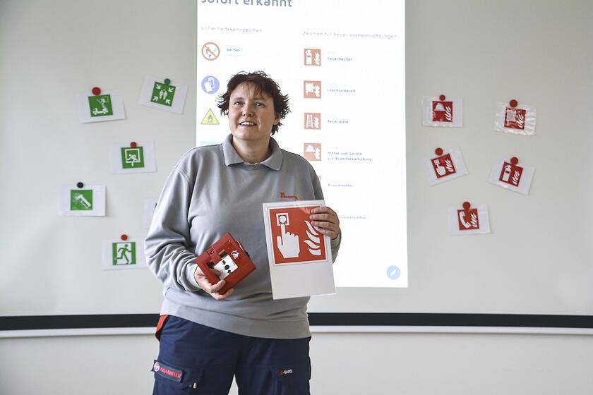 Eine Lehrkraft der Brandschutz-Ausbildung steht vor einer Leinwand