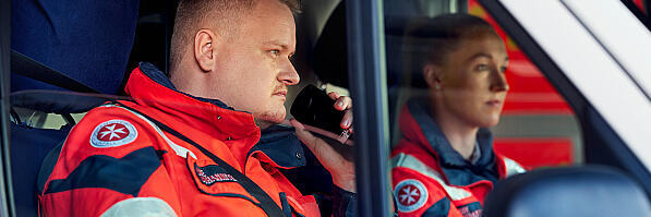 Ein Mitarbeiter aus dem Rettungsdienst nimmt im Rettungswagen Kontakt über ein Funkgerät auf.