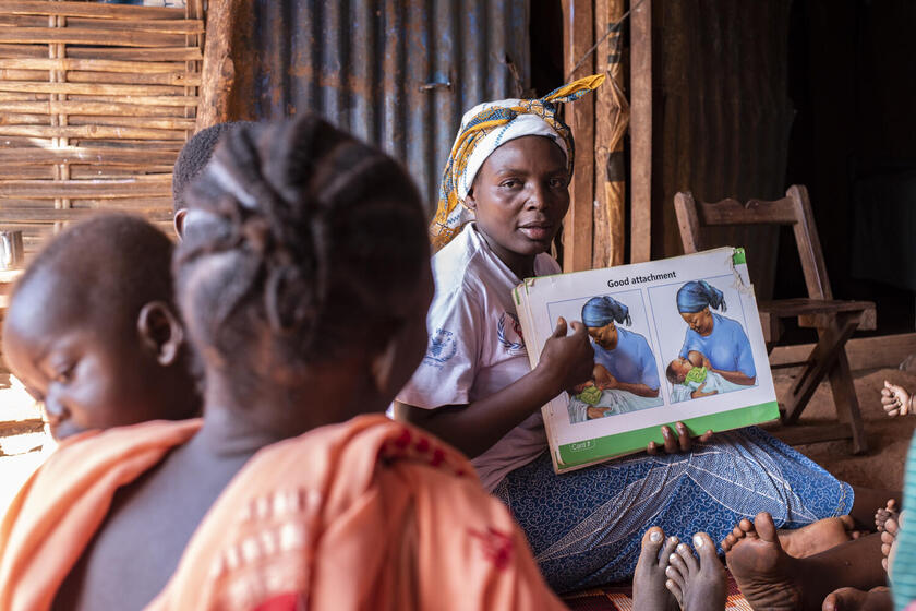 Eine Mutter mit einem Infoplakat über das Stillen klärt andere Mütter auf.