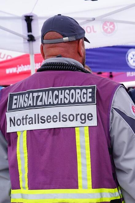 Man erkennt den Rücken eines Mannes, auf dem "PSNV" steht