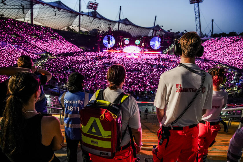 Sanitätskräfte blicken auf leuchtende Menschenmenge bei Konzert im Olympiastadion