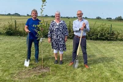 Amtsvorsteher Harm Schloe, Kita-Leitung Tanja Burkhard und der leitende Verwaltungsbeamte Christopher Stein mit dem zu setzenden Apfelbaum