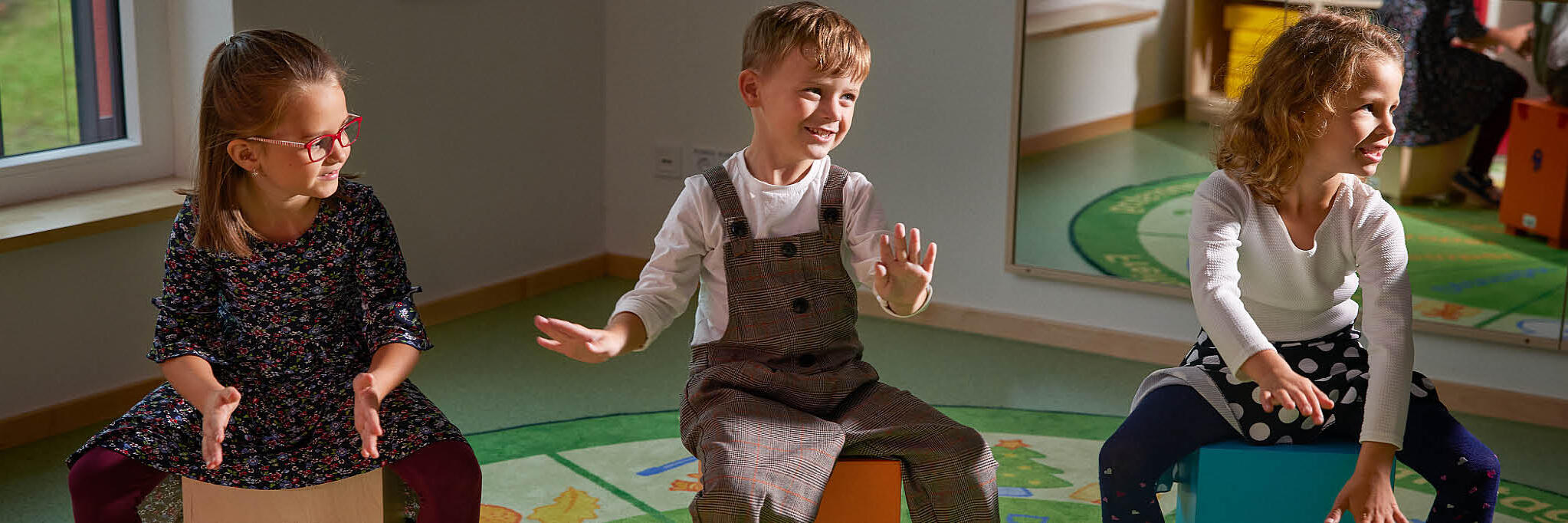 Drei Kinder sitzen auf Hüpfbällen in der Kita