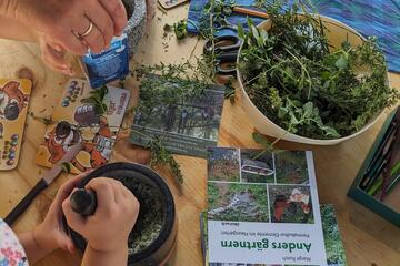 Ein Kind bereitet in einem Mörsertopf Kräutersalz.