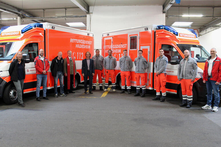 Mitarbeitende, Vorstände, Pfarrer und Gäste vor den beiden neuen Rettungswagen.