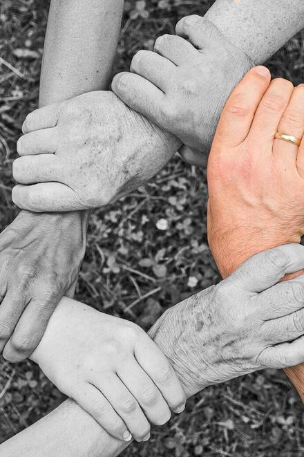 Mehrere Hände greifen ineinander und bilden einen Kreis als Symbol für Zusammenhalt.