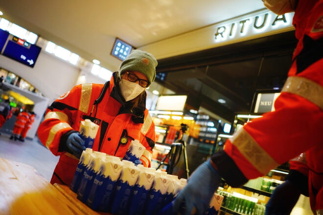 Ehrenamtliche der Johanniter-Kältehilfe verteilen Lebensmittel an Obdachlose.