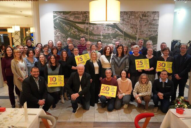 Gruppenbild von Jubilaren die Schilder mit den jeweiligen Dienstjahren nach oben halten