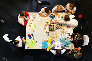 Kinder basteln an einem Tisch, Aufnahme von oben