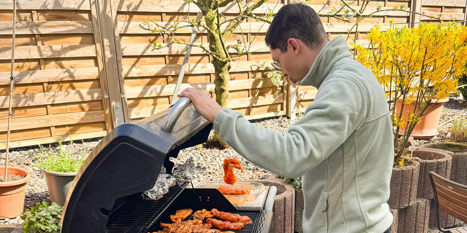 Ein junger Mann in einem Garten an einem Grill