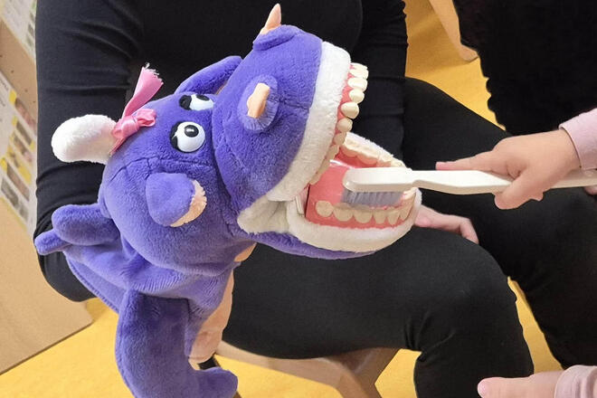 Zahnmonster Nikoletta lässt sich geduldig die Zähne eines Kindergartenkindes putzen.