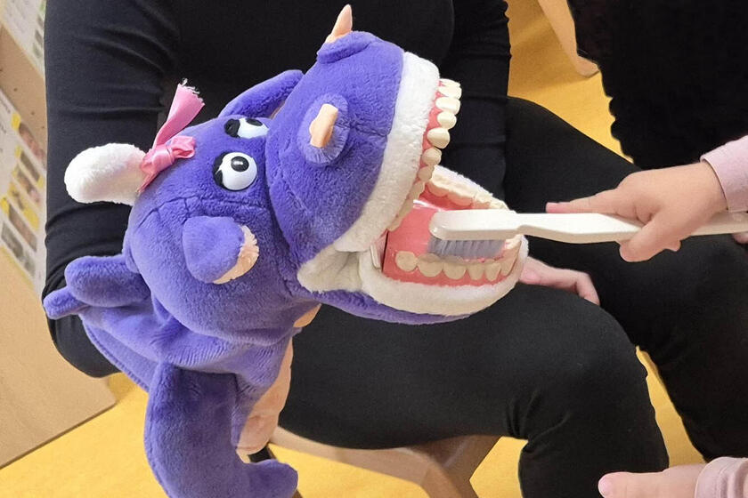 Zahnmonster Nikoletta lässt sich geduldig die Zähne eines Kindergartenkindes putzen.