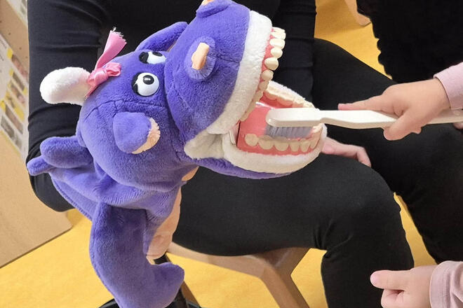 Zahnmonster Nikoletta lässt sich geduldig die Zähne eines Kindergartenkindes putzen.