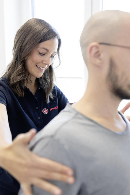 Eine Mitarbeiterin der Johanniter richtet einen Patientin an den Schultern aus.