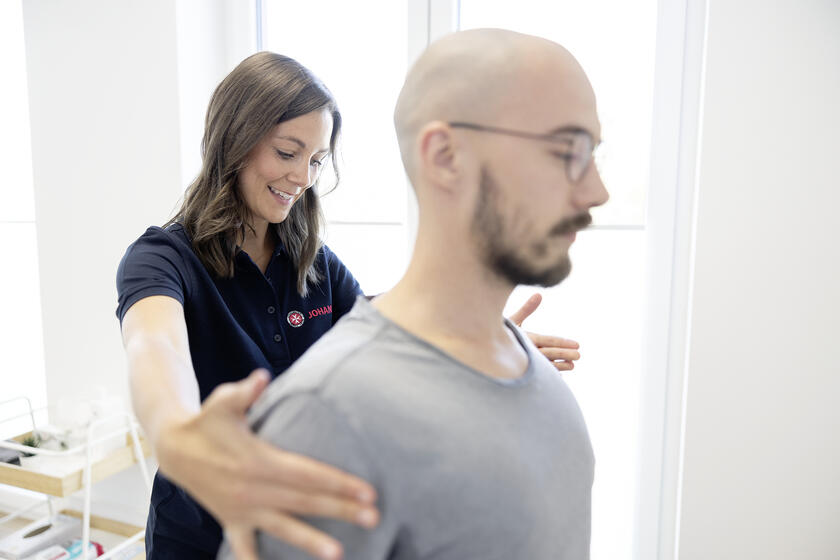 Eine Mitarbeiterin der Johanniter richtet einen Patientin an den Schultern aus.