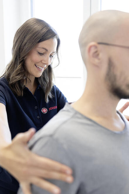 Eine Mitarbeiterin der Johanniter richtet einen Patientin an den Schultern aus.