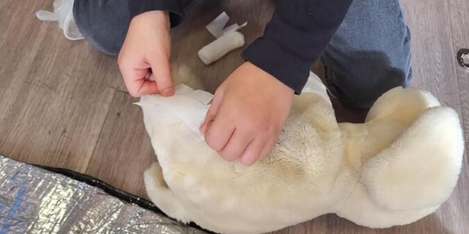 Kind versorgt einen Teddybär.