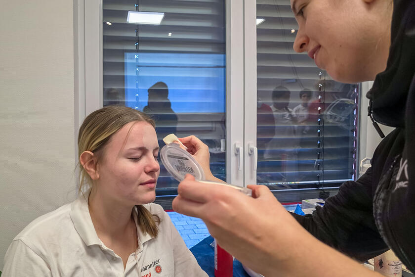 Eine Helferin der Johanniter schminkt einer Verletztendarstellerin das Gesicht.