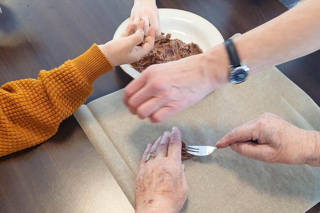 Hände von Jung und Alt formen aus Keksteich Wolkenkekse.