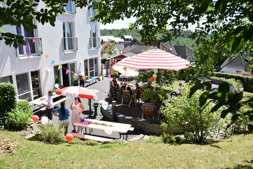 Viele Menschen stehen auf dem Platz vor Haus und feiern ein Sommerfest.