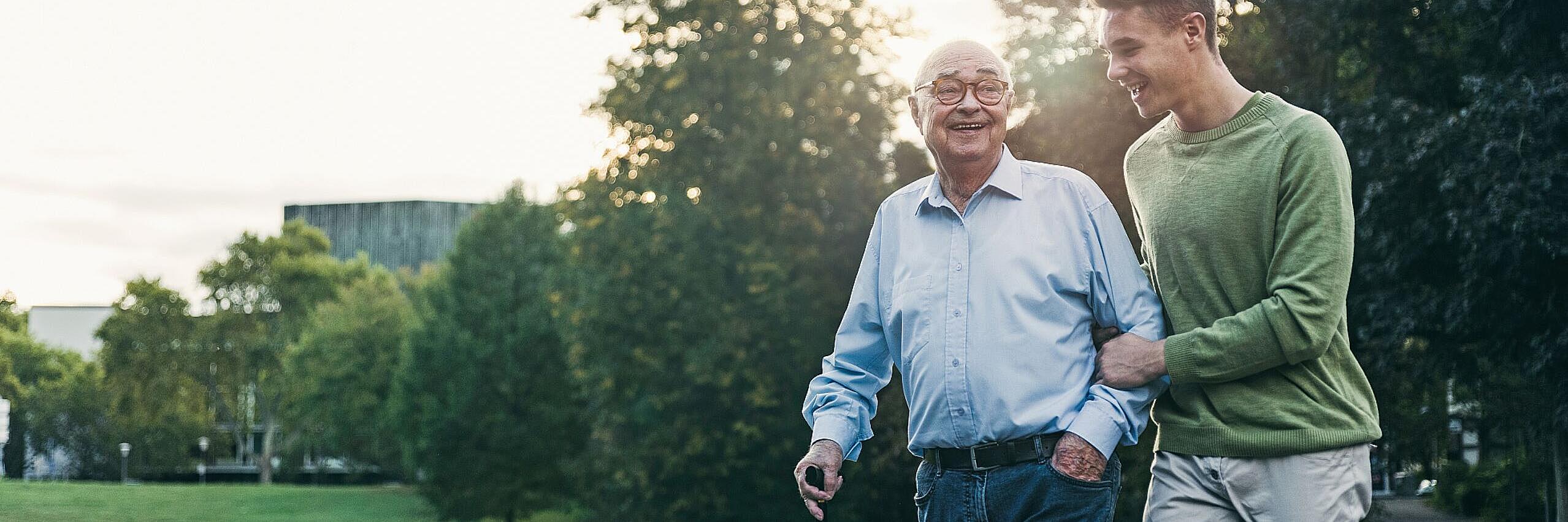 Älteres Paar geht gemeinsam durch einen Park und unterhält sich.