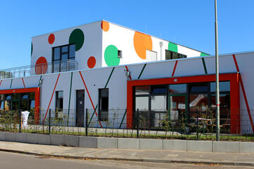 Ansicht der Kita mit ihren aufälligen Punkten in orange und grün von der Straßenseite aus. 