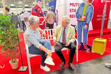 Zwei Personen im Gespräch auf der Plauderbank am Messestand des DEKT 2025 in Hannover