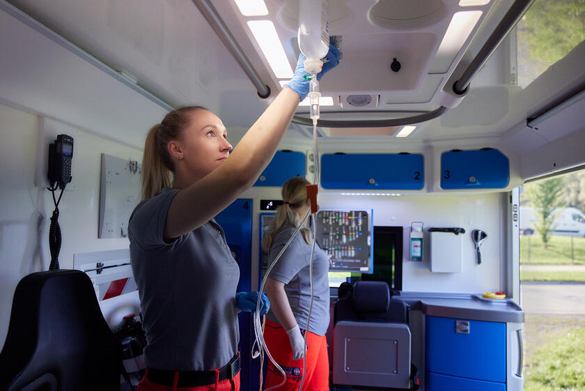 Notfallsanitäterin hängt im Rettungswagen einen Tropf an.