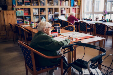 Zwei Bewohnerinnen malen an großen Tischen im Freizeitraum