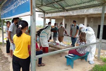 Menschen in einmal Anzügen testen Menschen auf COVID-19