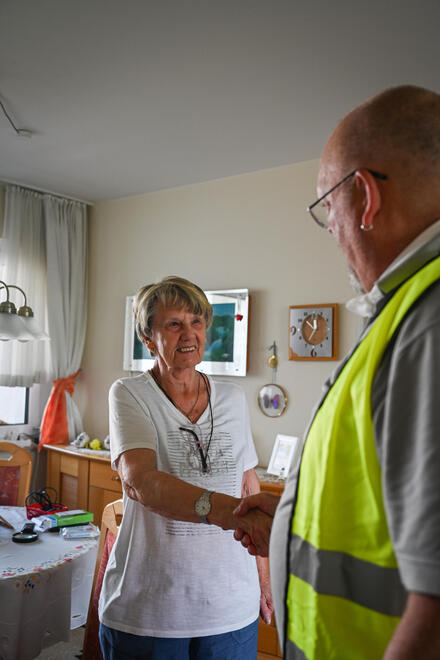 Ein Helfer der Psychosozialen Notfallversorgung tröstet eine ältere Dame in deren Wohnung.