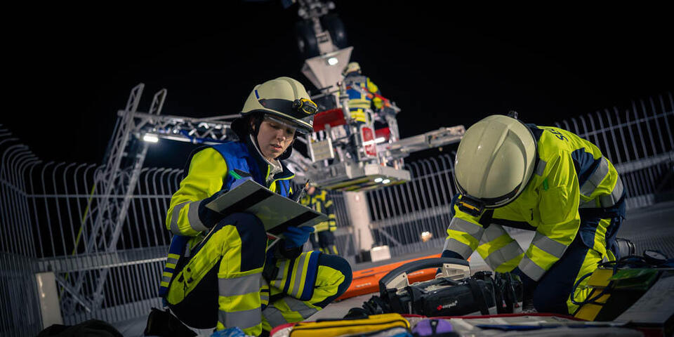 Eine Sanitäterin schreibt die Vitalwerte eines Patienten unterhalb der Boeing 747 im Technik Museum Speyer auf. Im Hintergrund ist die Drehleiter der Feuerwehr zu sehen.
