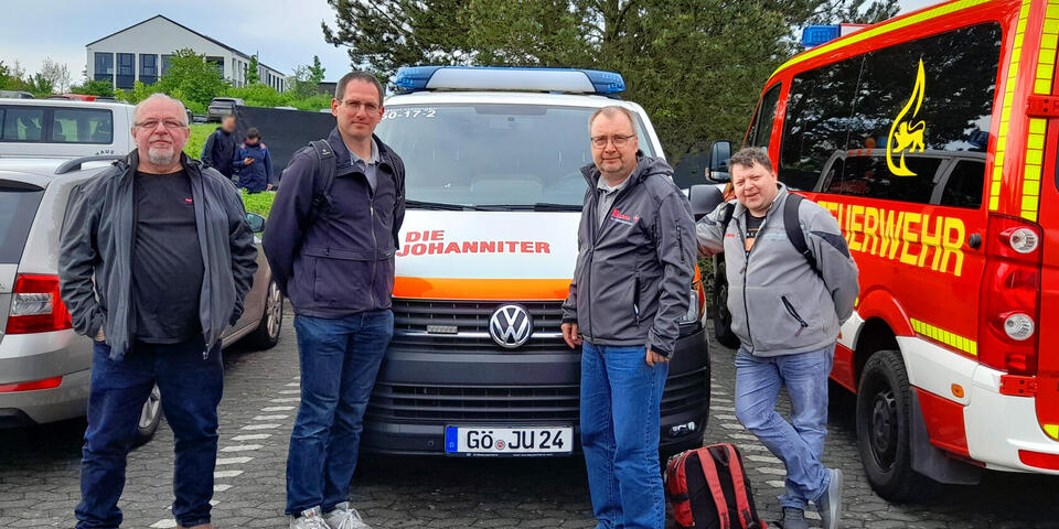 Vier Männer vor einem Johanniter-Fahrzeug