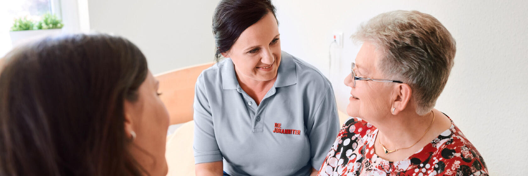 Eine Mitarbeiterin der Johanniter im Gespräch mit einer älteren Frau.