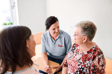 Eine Mitarbeiterin der Johanniter im Gespräch mit einer älteren Frau.